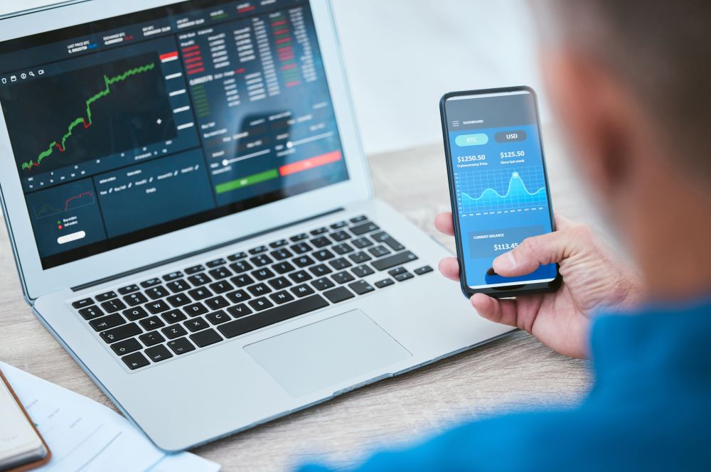 Man reviewing his return on investments on a phone and laptop